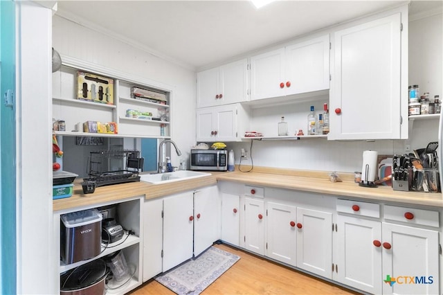 516 2nd St, Cuero, TX 77954 - kitchen featuring open shelves, stainless steel microwave, white cabinetry, light countertops, and ornamental molding