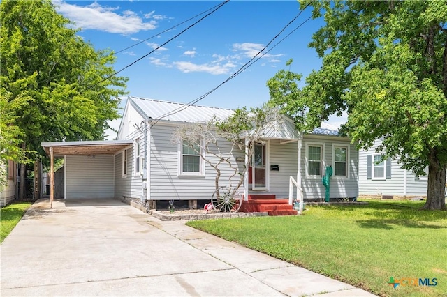 516 2nd St, Cuero, TX 77954 - view of front of house with concrete driveway, a front lawn, an attached carport, and a metal roof