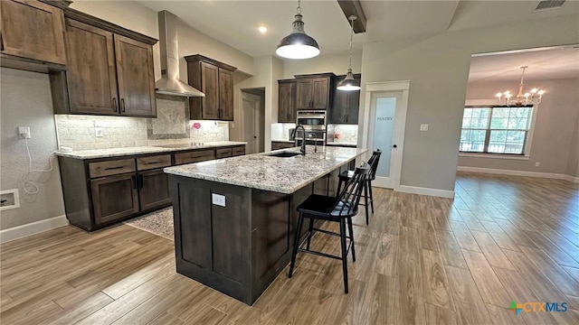 1026 County Road 3152, Kempner, TX 76539 - kitchen featuring wall chimney exhaust hood, a sink, a chandelier, dark brown cabinets, and tasteful backsplash