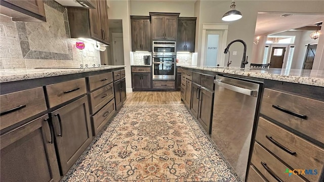 1026 County Road 3152, Kempner, TX 76539 - kitchen featuring stainless steel appliances, dark brown cabinets, light stone counters, a sink, and decorative backsplash