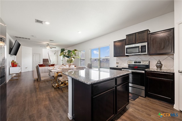 kitchen with a kitchen island, backsplash, appliances with stainless steel finishes, dark brown cabinets, and dark hardwood / wood-style flooring