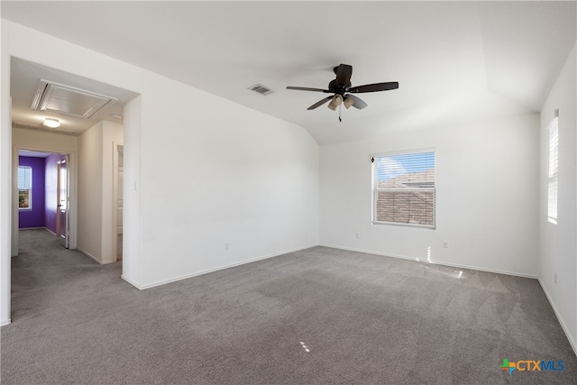 carpeted spare room with plenty of natural light, ceiling fan, and vaulted ceiling