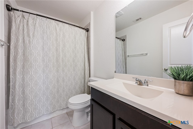 bathroom with toilet, vanity, and tile patterned flooring