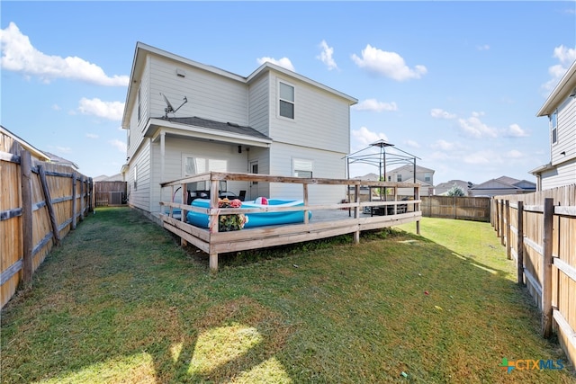 back of house featuring a wooden deck and a yard