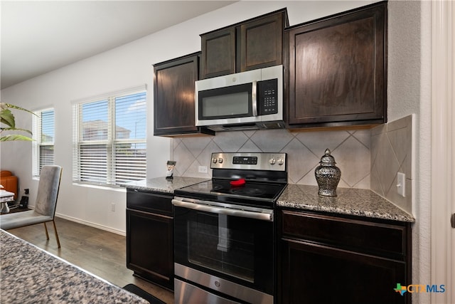 kitchen featuring wood-type flooring, backsplash, appliances with stainless steel finishes, dark brown cabinetry, and stone counters