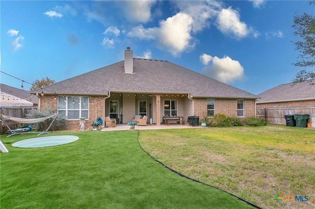 rear view of property featuring a patio area and a yard