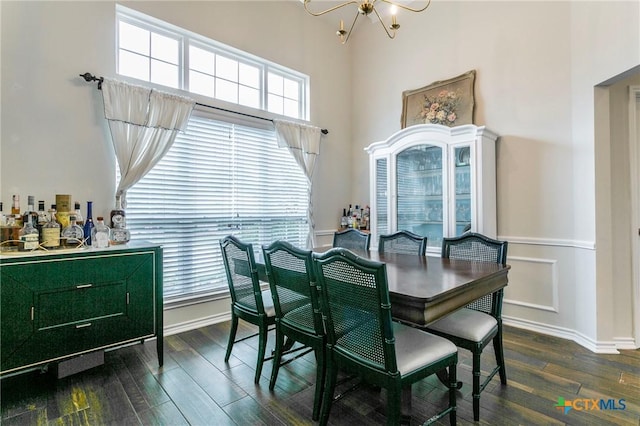 dining space featuring dark wood-type flooring, a high ceiling, and an inviting chandelier