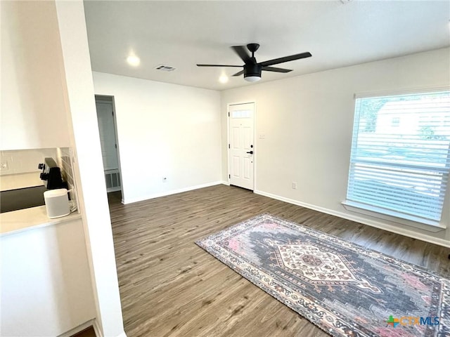 foyer with ceiling fan, visible vents, baseboards, and wood finished floors