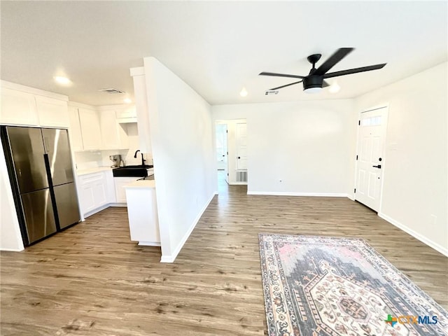 interior space featuring visible vents, white cabinetry, a sink, wood finished floors, and stainless steel fridge