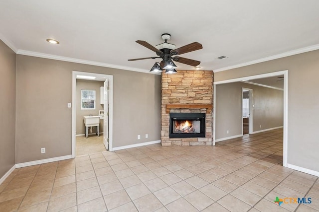 unfurnished living room featuring ceiling fan, light tile patterned floors, ornamental molding, and a fireplace