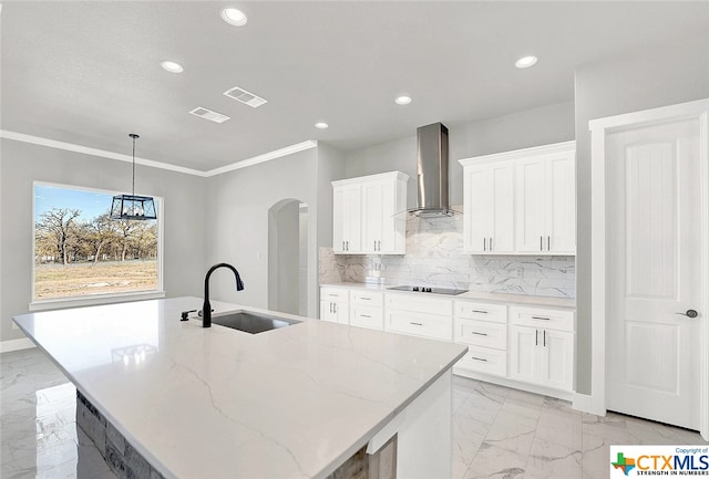 kitchen featuring white cabinetry, sink, wall chimney exhaust hood, and a center island with sink