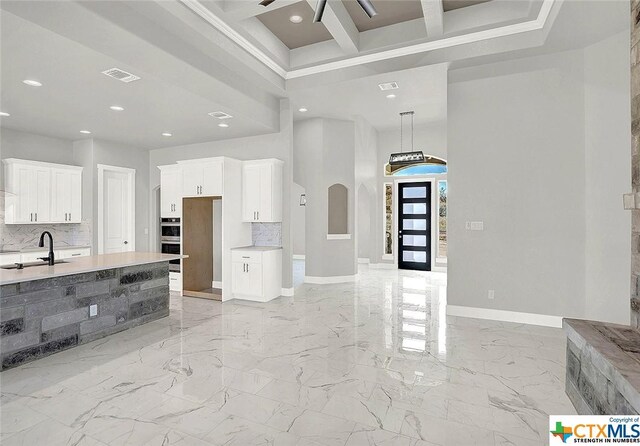 105 Hondo Rdg, La Vernia, TX 78121 - kitchen with a towering ceiling, a sink, tasteful backsplash, baseboards, and white cabinets