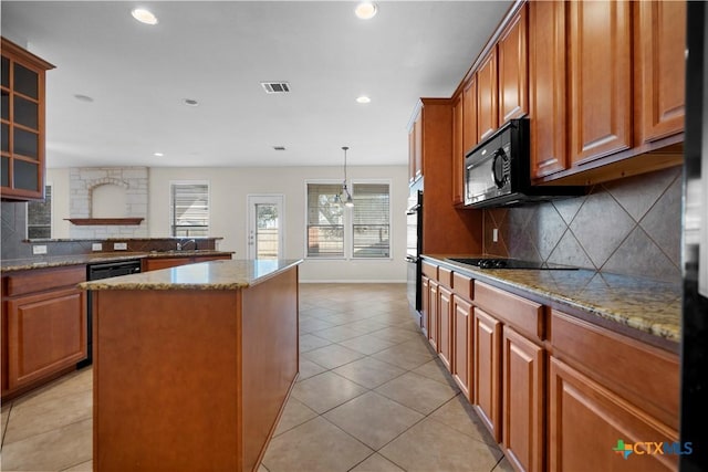 kitchen featuring a kitchen island, glass insert cabinets, light tile patterned floors, stone countertops, and black appliances