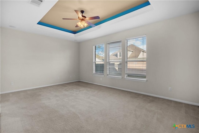 spare room with visible vents, baseboards, a tray ceiling, carpet flooring, and a ceiling fan