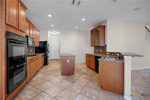 kitchen featuring visible vents, a peninsula, a sink, black appliances, and a center island