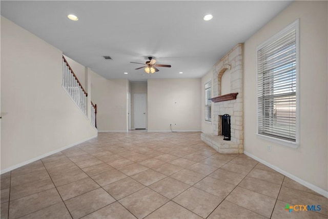 unfurnished living room featuring light tile patterned floors, baseboards, a fireplace, ceiling fan, and stairs