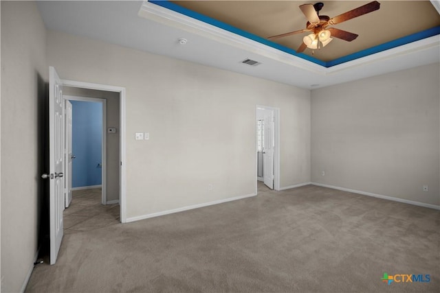 unfurnished room with a tray ceiling, baseboards, visible vents, and carpet floors