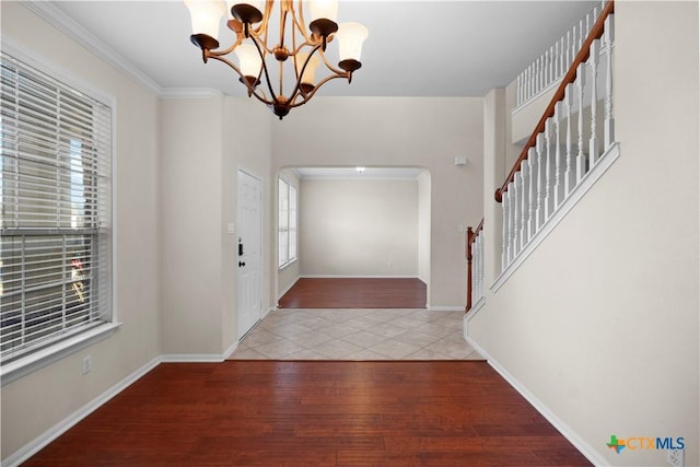 foyer entrance featuring stairway, wood finished floors, baseboards, an inviting chandelier, and arched walkways