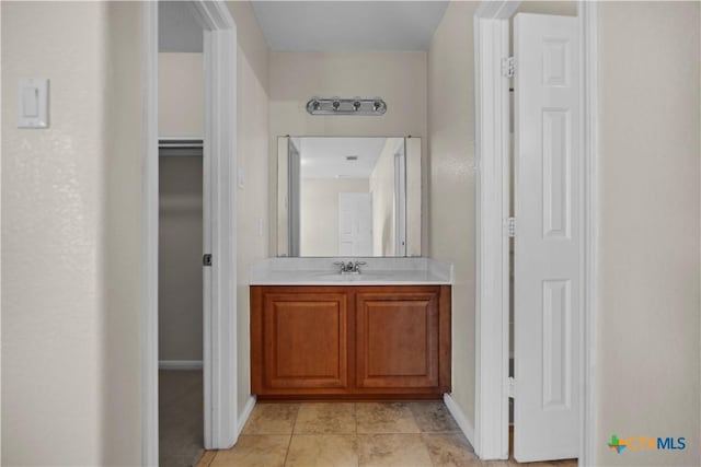 bathroom with baseboards, a spacious closet, vanity, and tile patterned flooring