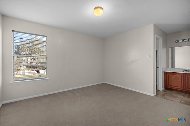 unfurnished bedroom with a sink, baseboards, and light carpet