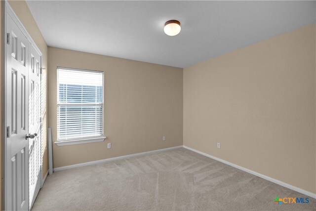 unfurnished bedroom with baseboards, a closet, and light carpet