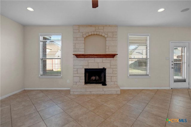 unfurnished living room with light tile patterned floors, baseboards, and a stone fireplace