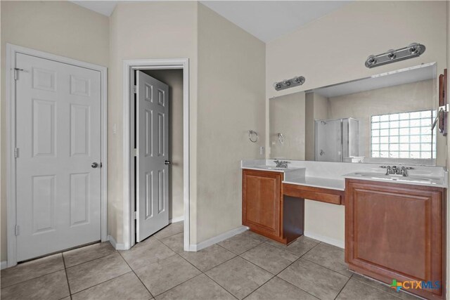 full bath with tile patterned flooring, a sink, a stall shower, and double vanity