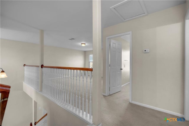 corridor featuring visible vents, baseboards, attic access, and carpet flooring