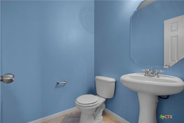 bathroom featuring tile patterned floors, baseboards, toilet, and a sink