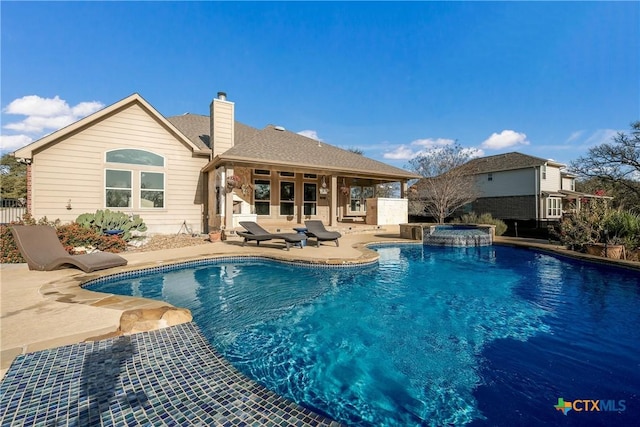 view of swimming pool featuring a pool with connected hot tub, a patio, and fence