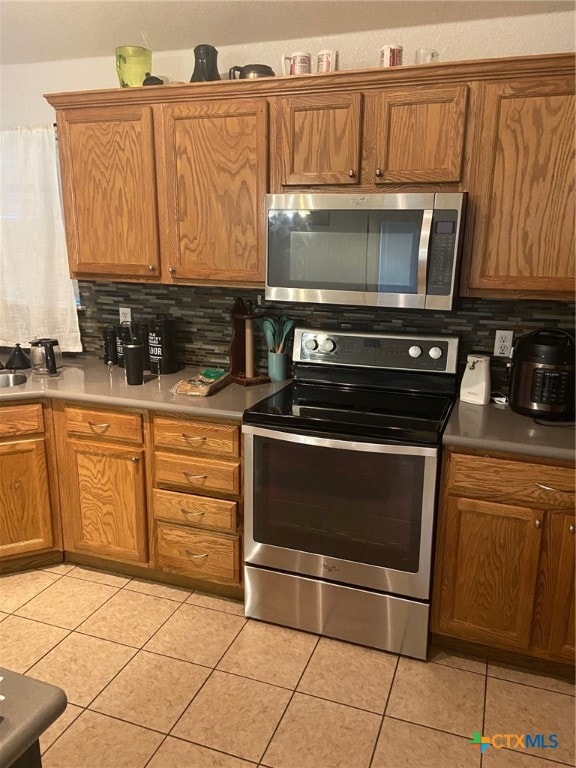 kitchen featuring appliances with stainless steel finishes, decorative backsplash, and light tile patterned floors