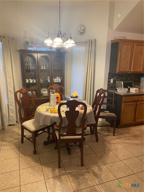 dining space featuring light tile patterned flooring, a high ceiling, and an inviting chandelier