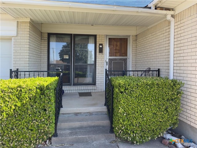 entrance to property featuring brick siding and covered porch