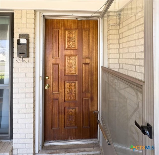 view of exterior entry featuring brick siding