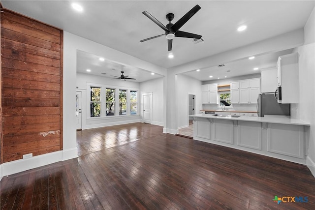 unfurnished living room with dark hardwood / wood-style flooring and ceiling fan