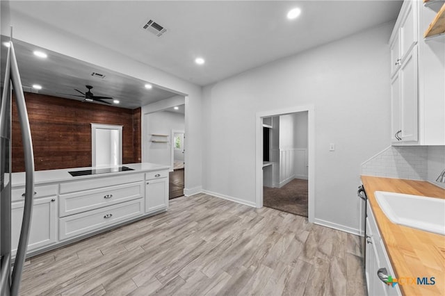 interior space featuring hardwood / wood-style floors, tasteful backsplash, ceiling fan, and sink