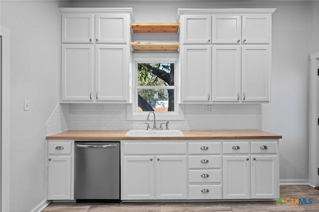 kitchen with wood counters, white cabinets, stainless steel dishwasher, and sink