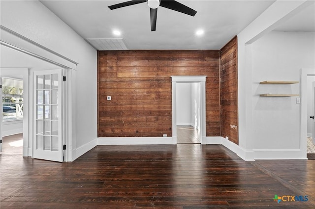 unfurnished room with wooden walls, dark hardwood / wood-style flooring, and ceiling fan