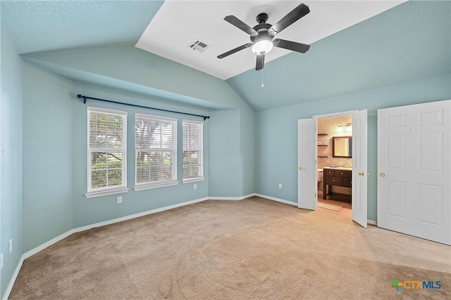 unfurnished bedroom with vaulted ceiling, light carpet, ceiling fan, and ensuite bathroom