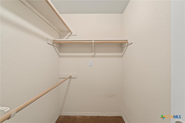 spacious closet featuring dark colored carpet