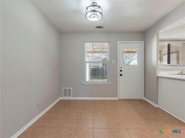 doorway with light tile patterned floors and a textured ceiling