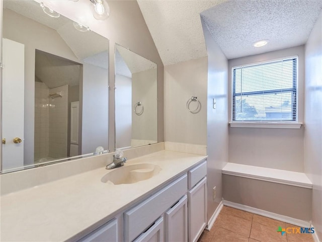 bathroom featuring tile patterned floors, a textured ceiling, vanity, tiled shower, and lofted ceiling