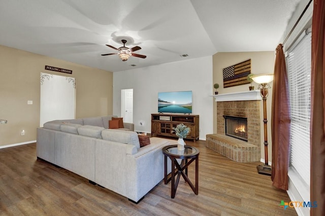 living room featuring hardwood / wood-style flooring, a brick fireplace, and ceiling fan