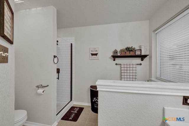 bathroom with tile patterned flooring, a shower with shower door, and toilet