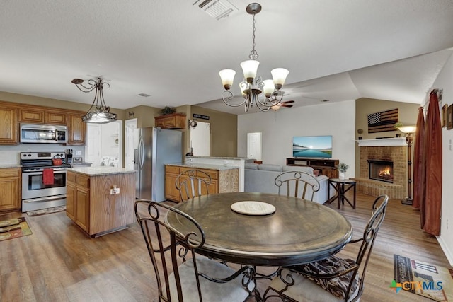 dining room with a fireplace, light hardwood / wood-style floors, and a chandelier