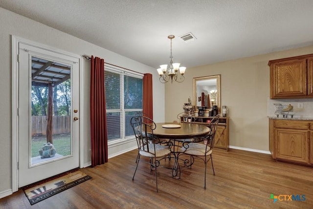 dining area featuring an inviting chandelier, hardwood / wood-style floors, and a textured ceiling