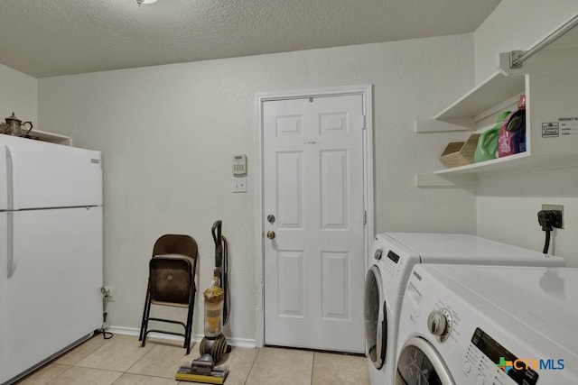 washroom with separate washer and dryer, light tile patterned floors, and a textured ceiling