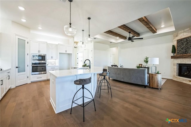 kitchen featuring decorative light fixtures, built in microwave, white cabinetry, a breakfast bar area, and oven