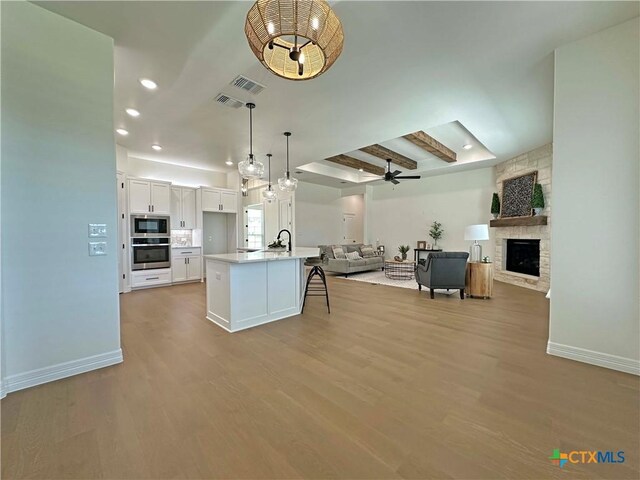 4316 Sunflower Ln, Temple, TX 76502 - kitchen with custom range hood, stainless steel gas stovetop, wood finished floors, pendant lighting, and tasteful backsplash