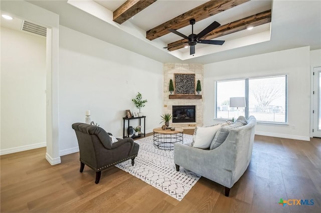 living room with ceiling fan, a tray ceiling, a fireplace, and hardwood / wood-style floors